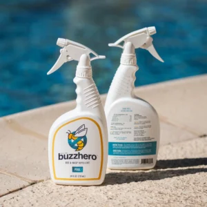 Two bottles of BuzzHero bee and wasp repellent spray labeled for pool use, shown poolside with one bottle facing front and the other showing the back label.